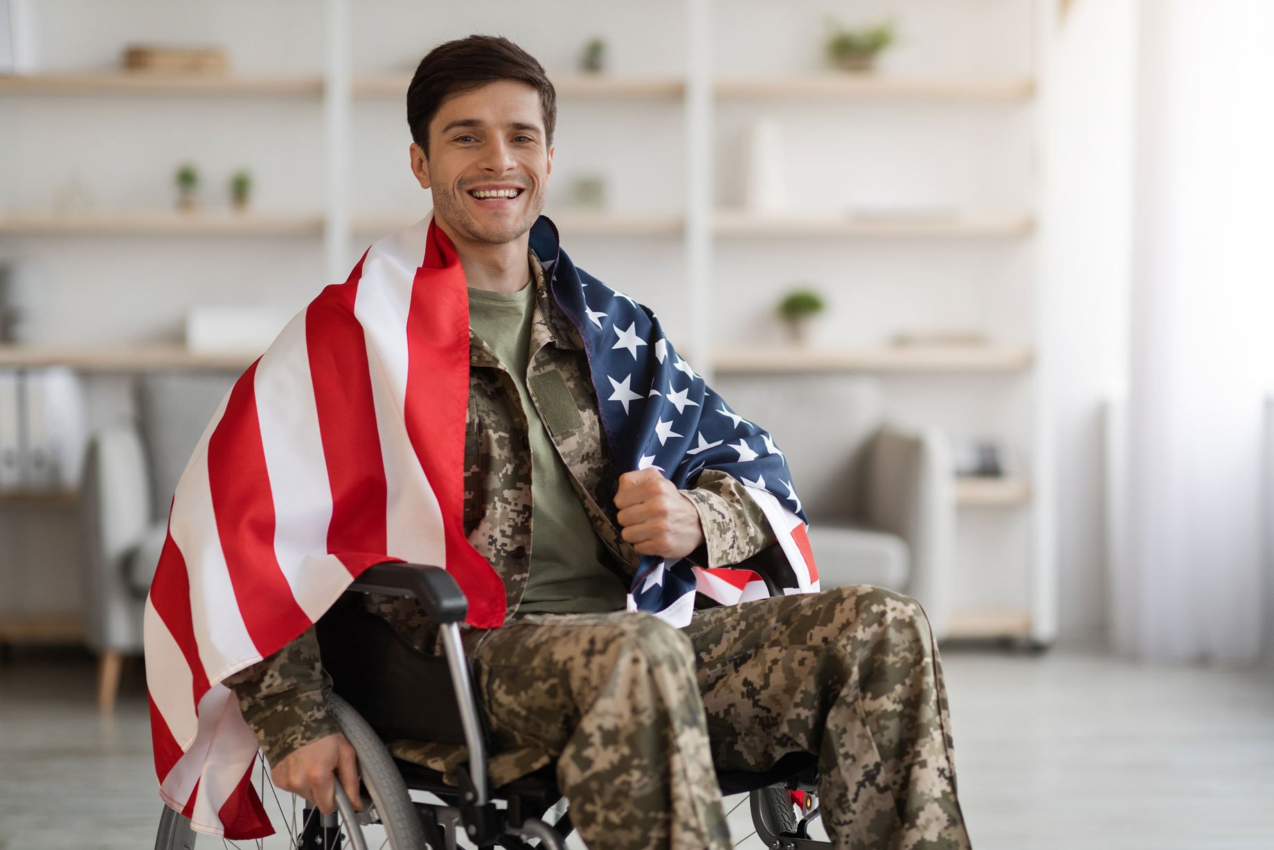 Disabled veteran wrapped in an American flag sitting in a wheelchair