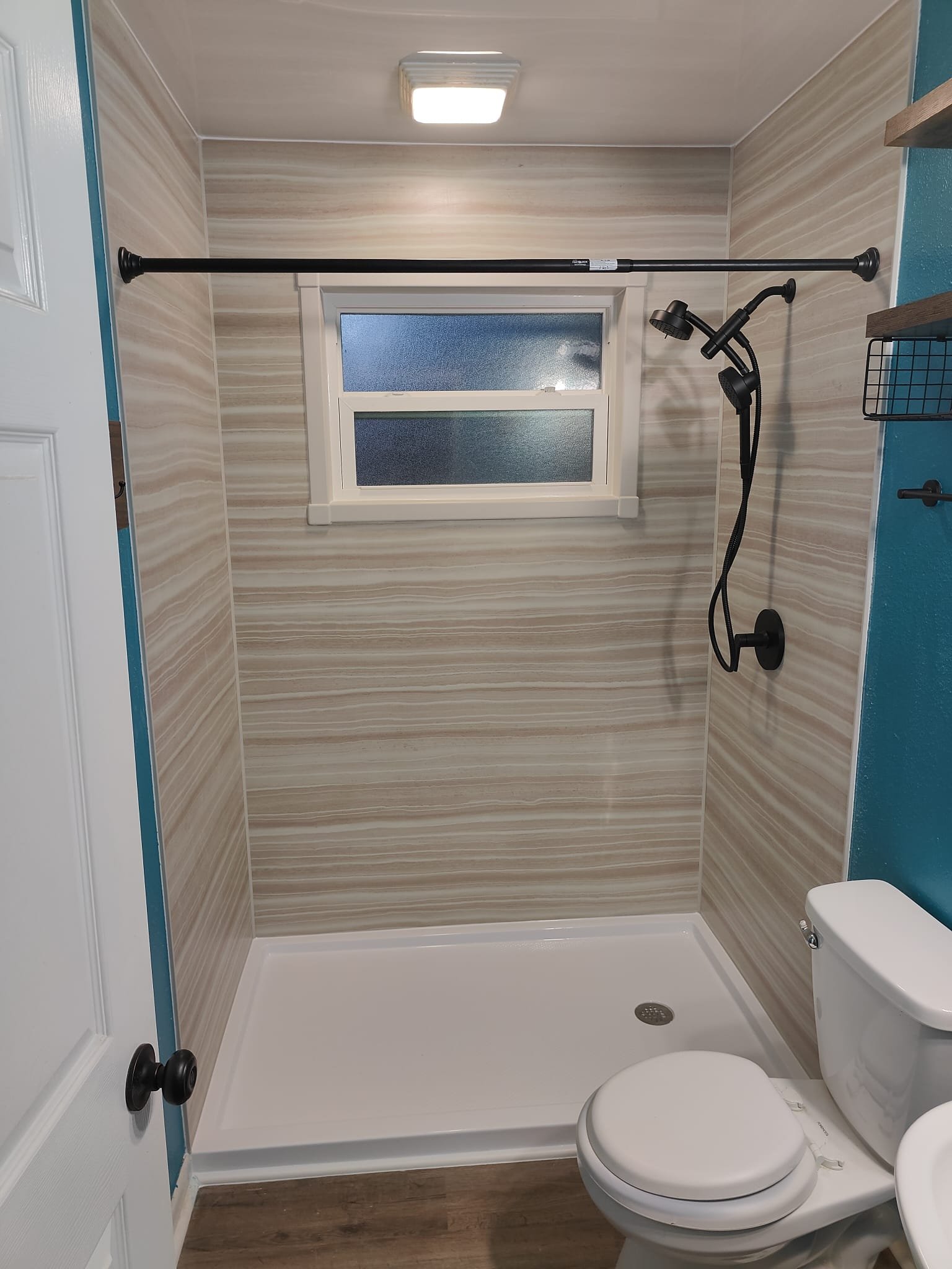 Walk-in shower with wood-look wall panels and rainfall shower head
