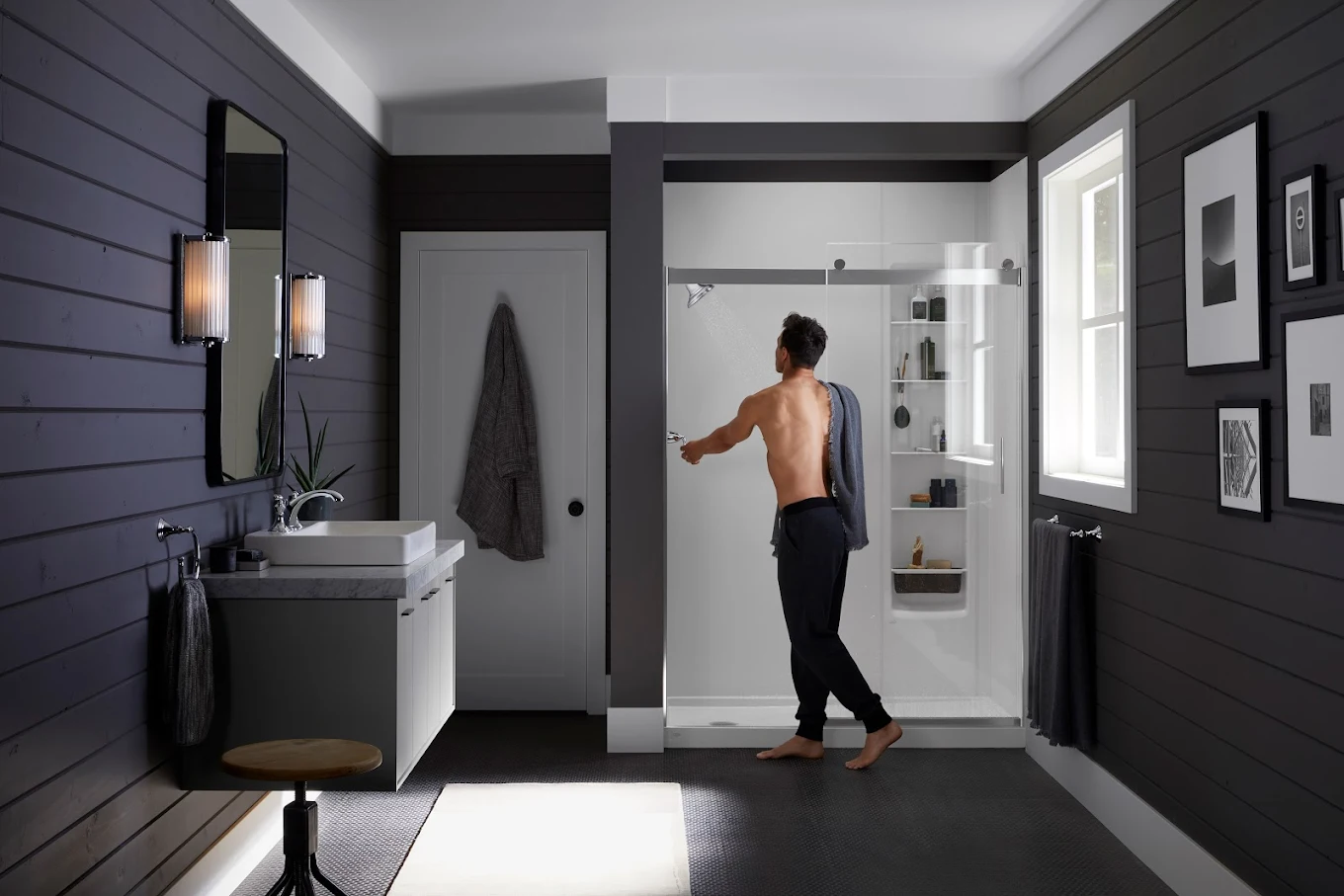 Man preparing to shower in a spacious walk-in shower with built-in shelving