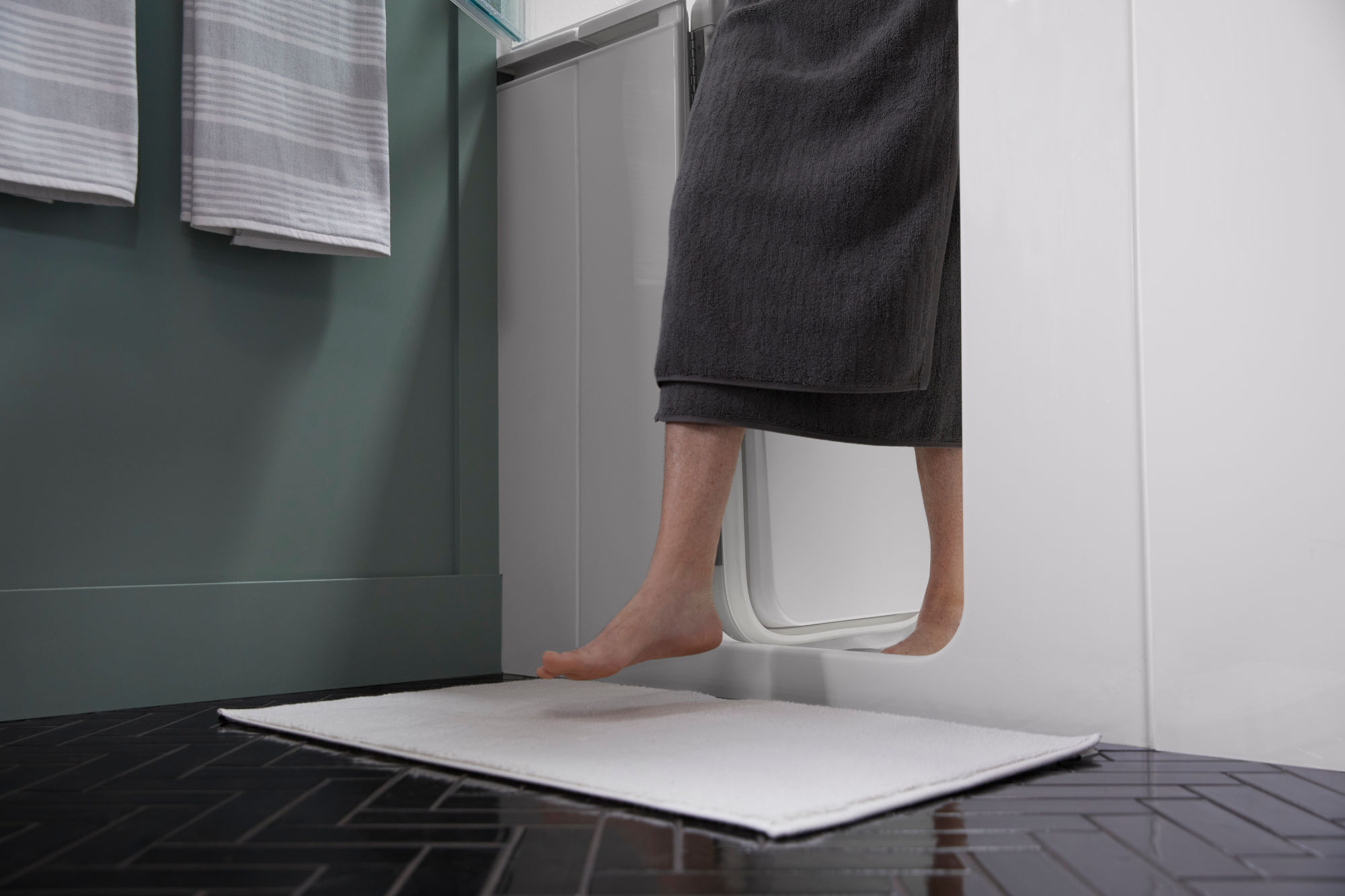 A woman stepping out of a walk-in bathtub onto a bath mat.