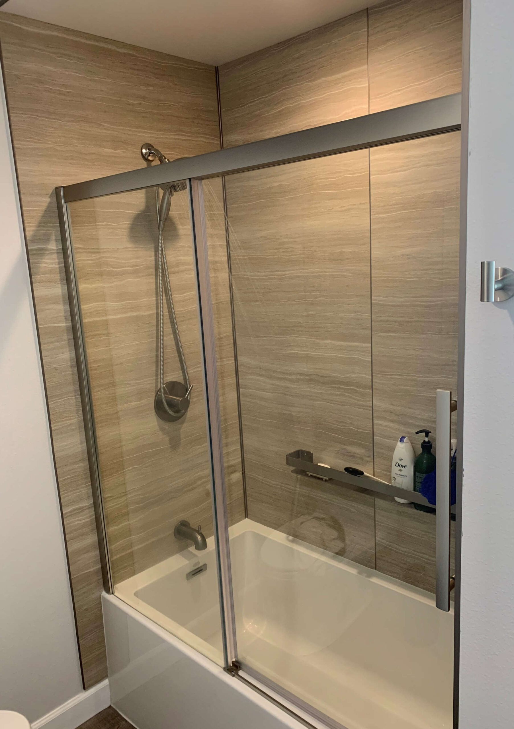 Bathtub and shower combination with sliding glass doors and beige wall panels