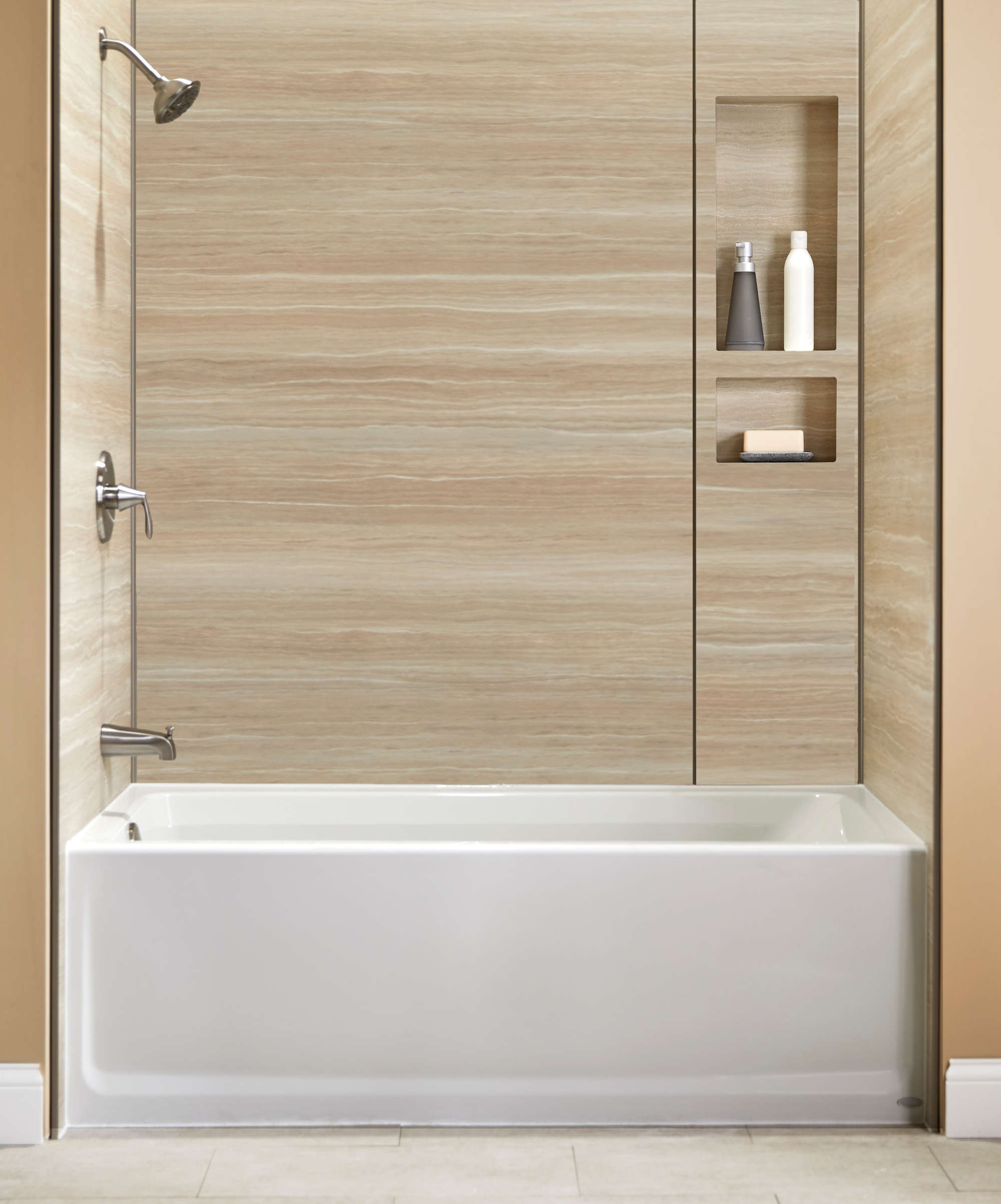 Bathtub and shower combination with beige wall panels and built-in storage niches
