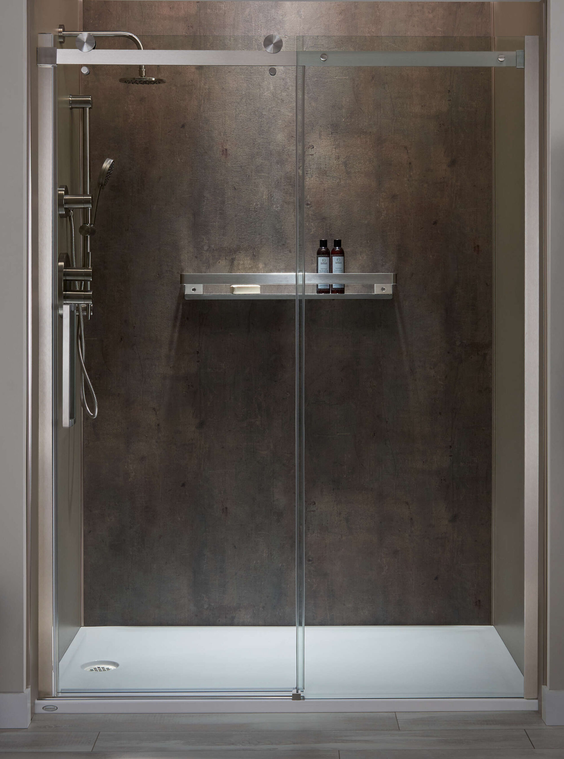 A walk in shower with a sliding glass door and a shelf.