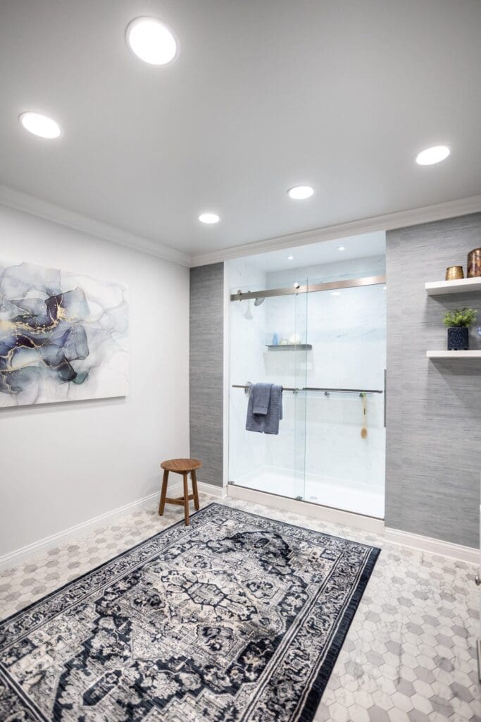 Bathroom with glass walk-in shower, sliding shower door handle, wall-mounted shower head, and recessed ceiling lights