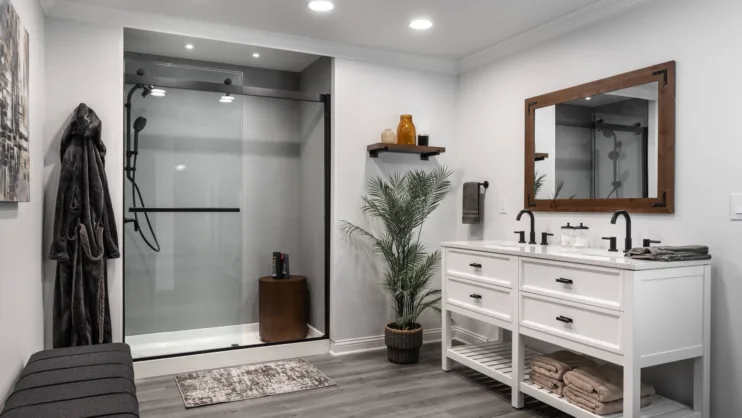 Gray bathroom with black-framed shower enclosure and white vanity